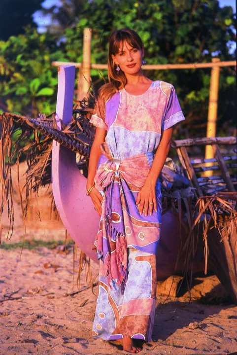 Woman in colorful dress standing by purple canoe