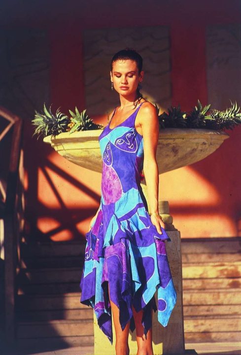 Woman in vibrant blue dress standing by red wall